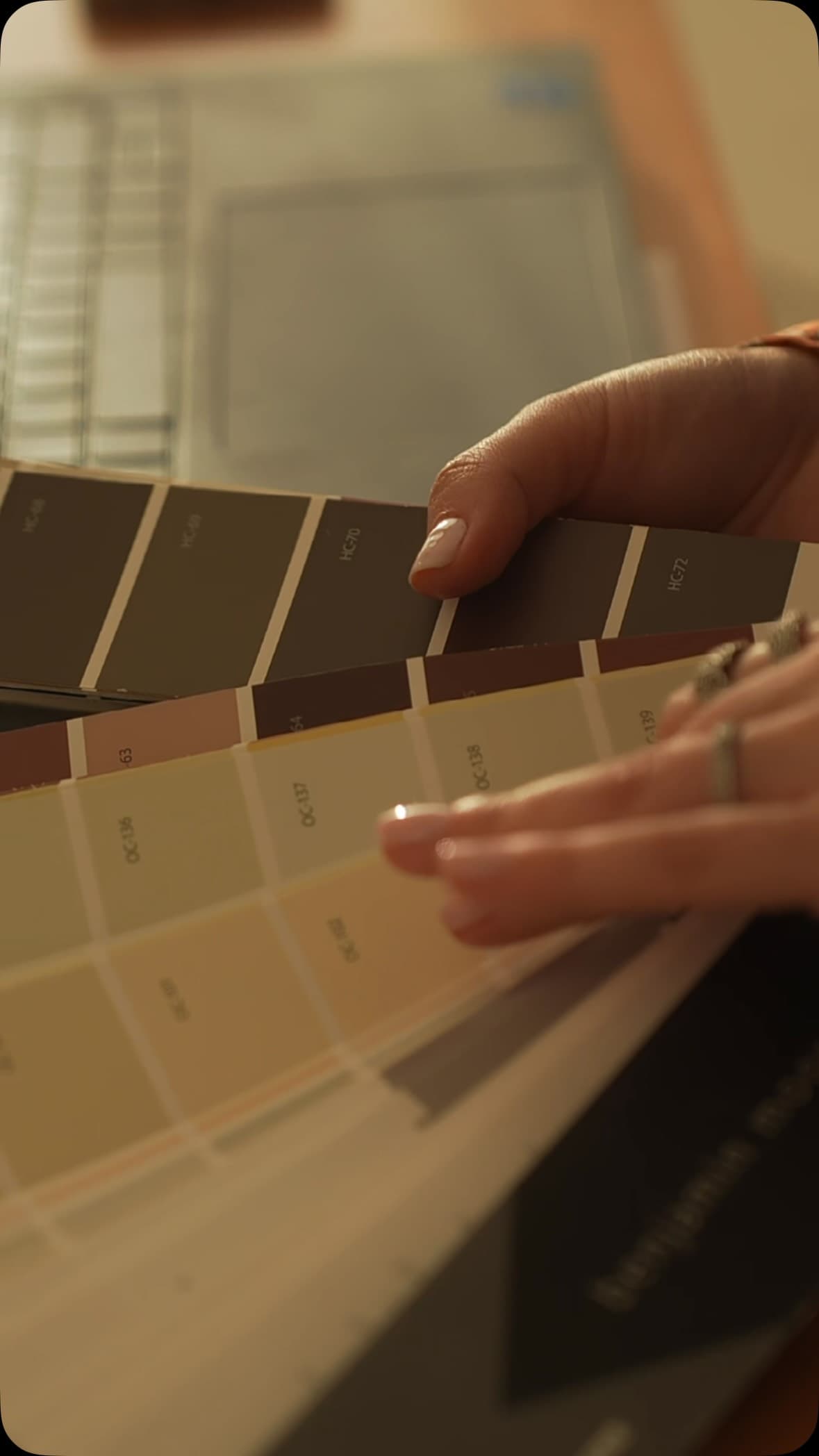 Hands comparing warm neutral and deep brown paint decks during a Studio Black Oak selection review.